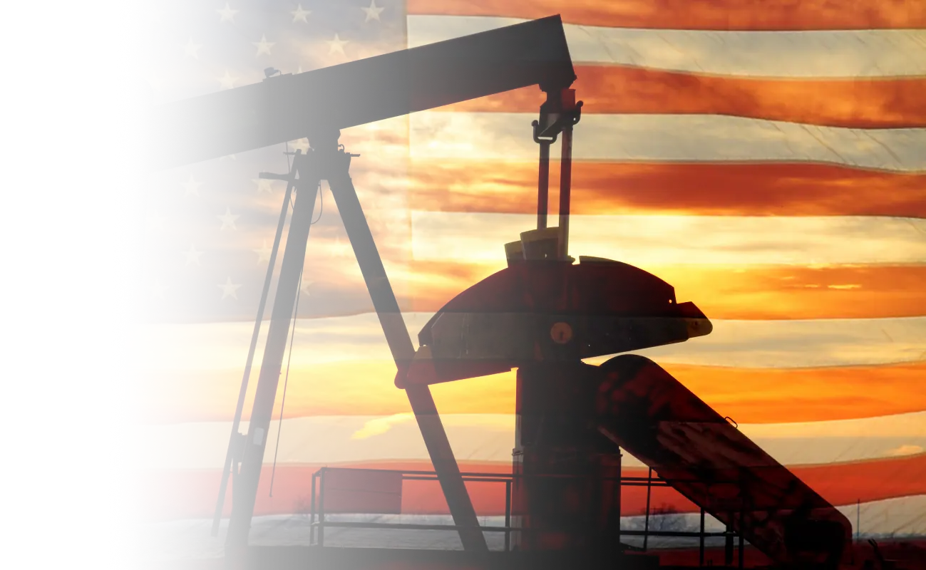 Oil pump jack in front of an American flag at sunset